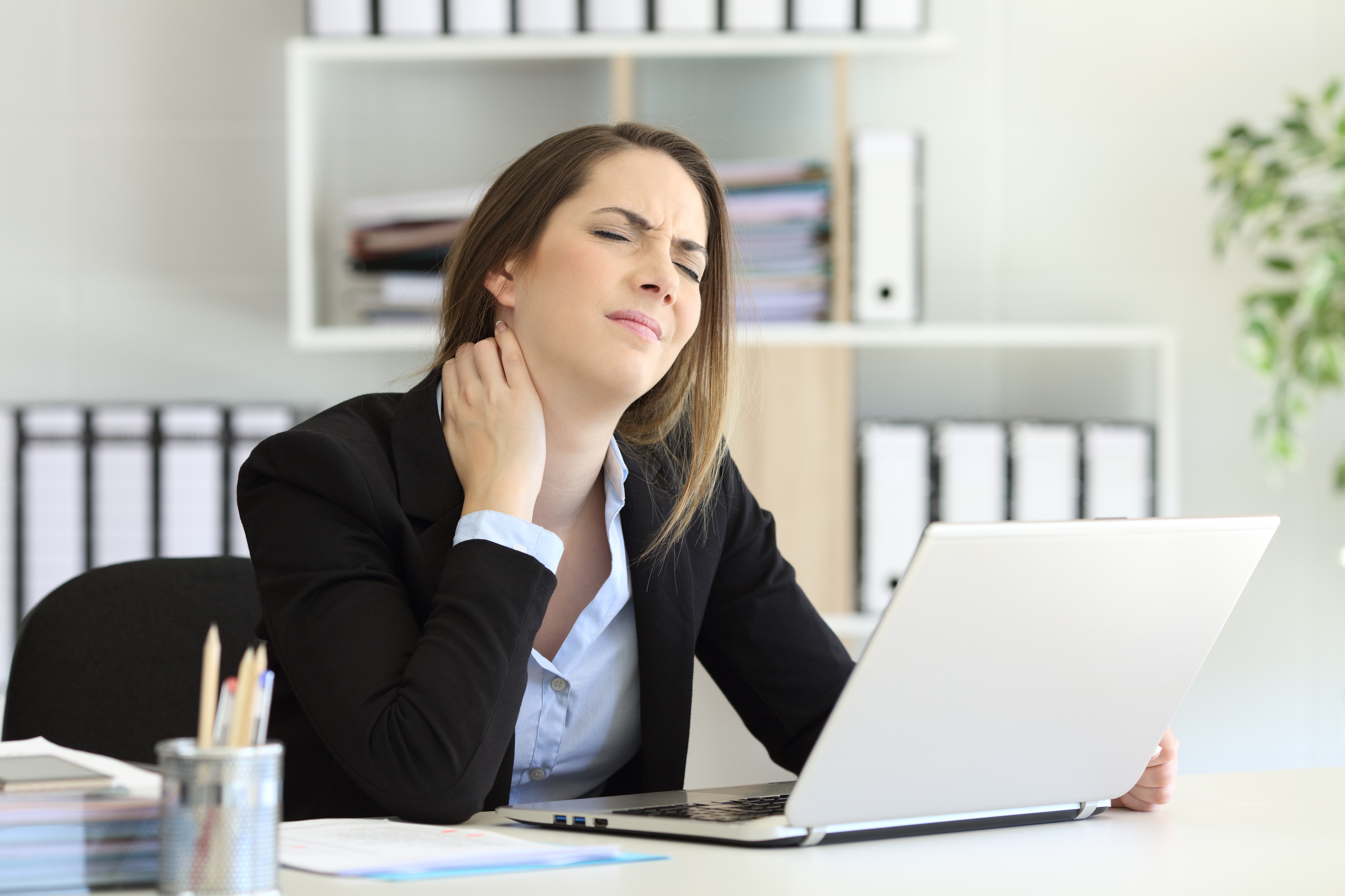 Office worker suffering neck ache sitting in a desktop
